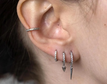 Silver four earring stack set worn on the ear: ear cuff and three huggie hoops with spike charms